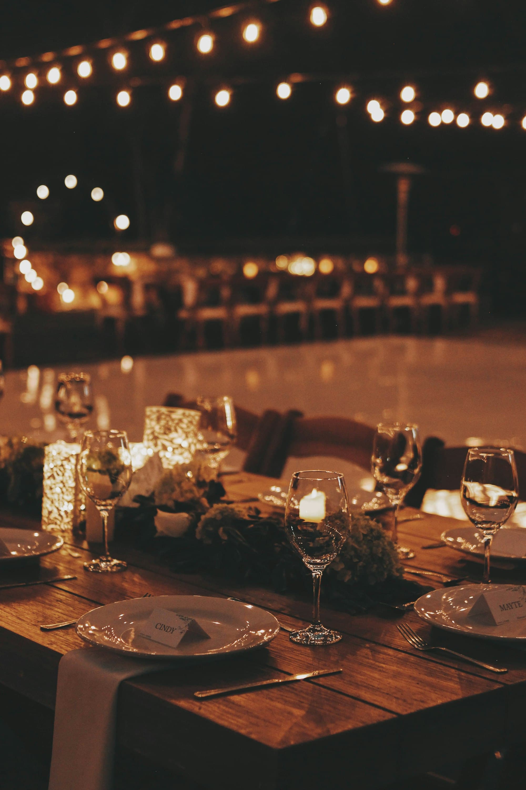 Gedeckte Tafel mit Kerzen und Lichterketten am Abend
